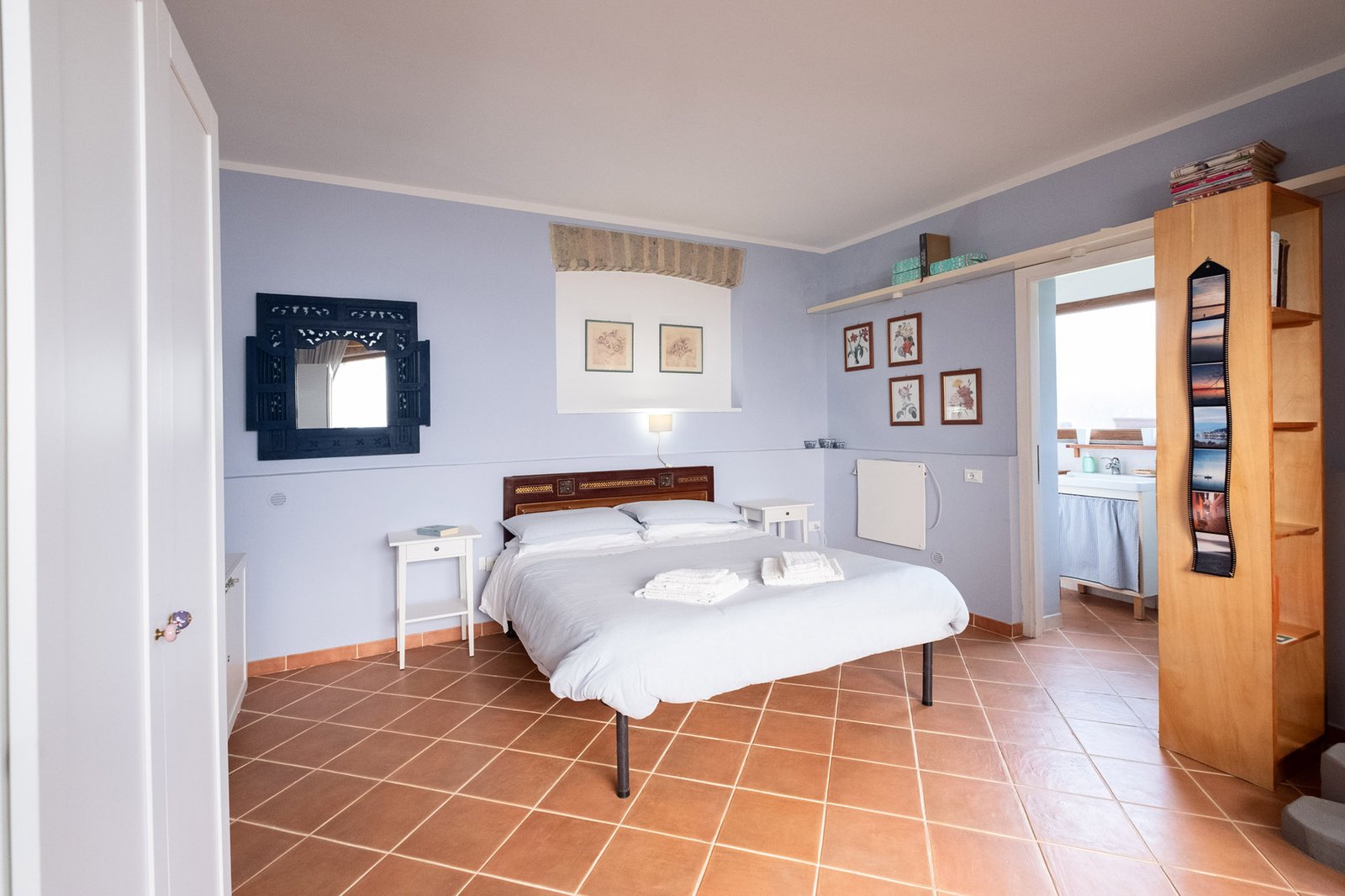 letto matrimoniale con comodini e armadio e vista della zona bagno