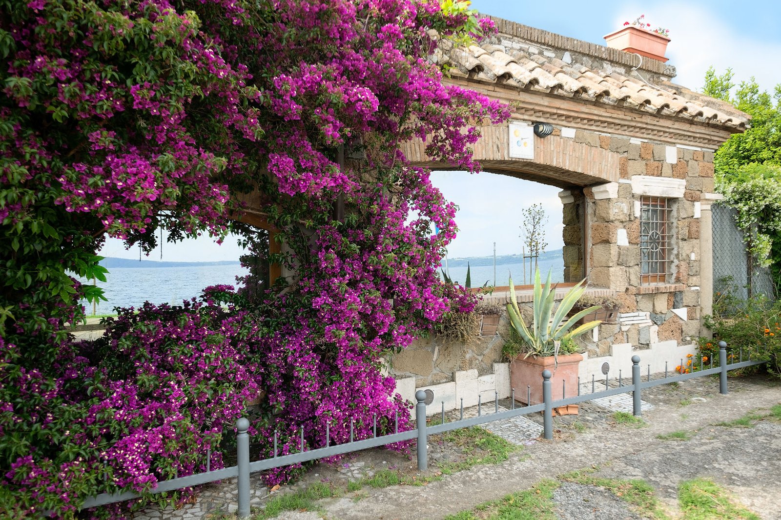 due grandi vetrate esterne della casa con rilfessi del lago e incorniciate dalla bucanvilla